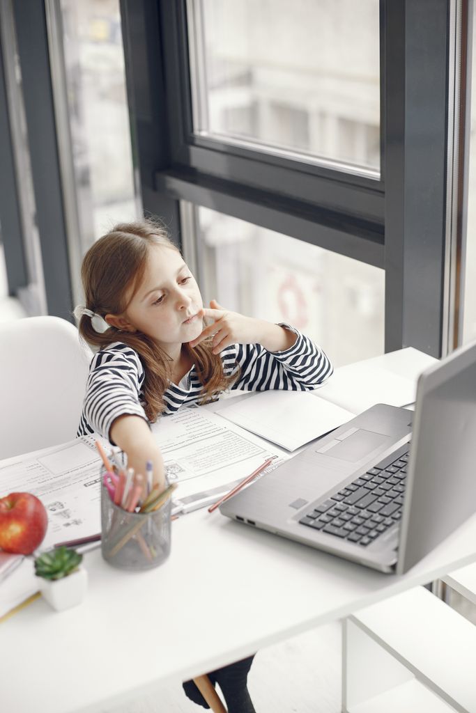 A young girl engaging in online learning at home using a laptop, emphasizing modern education.